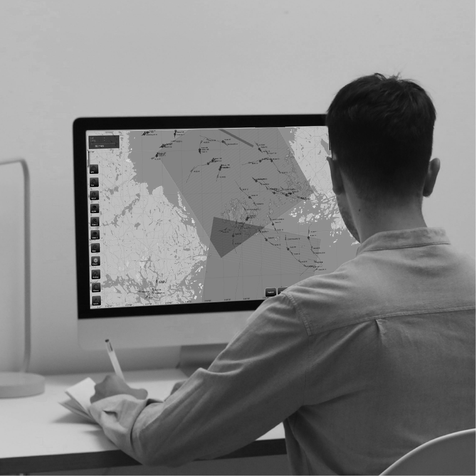 A person analyzing a map on a computer monitor, taking notes while focusing on specific details, representing data processing and geographic analysis in airborne surveillance technology.